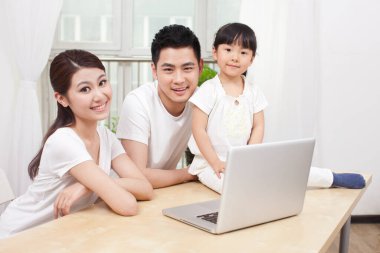 Ailesiyle birlikte dizüstü bilgisayar kullanan küçük kız.