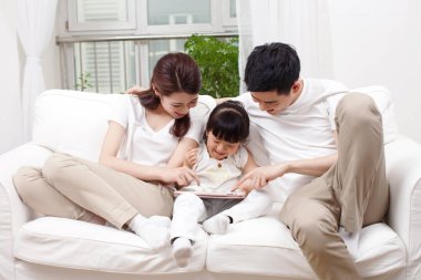 Ailesiyle birlikte dizüstü bilgisayar kullanan küçük kız.