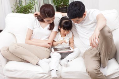 Ailesiyle birlikte dizüstü bilgisayar kullanan küçük kız.