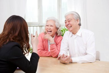 Genç bayan yaşlı çiftle konuşuyor.