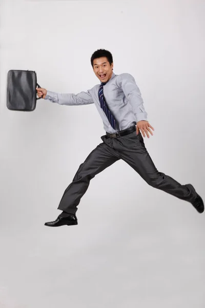 ブリーフケースを持って飛び跳ねる若いビジネスマン — ストック写真