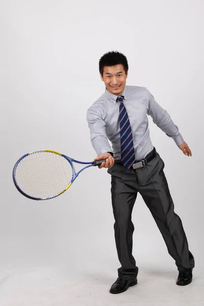 一个穿着商务服装打羽毛球的年轻人 — 图库照片