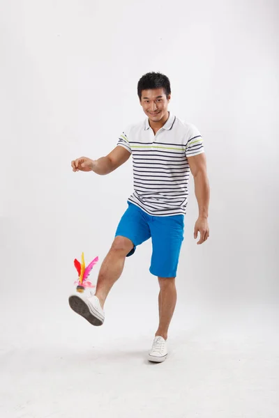 一个穿着休闲装的年轻人踢羽毛球 — 图库照片