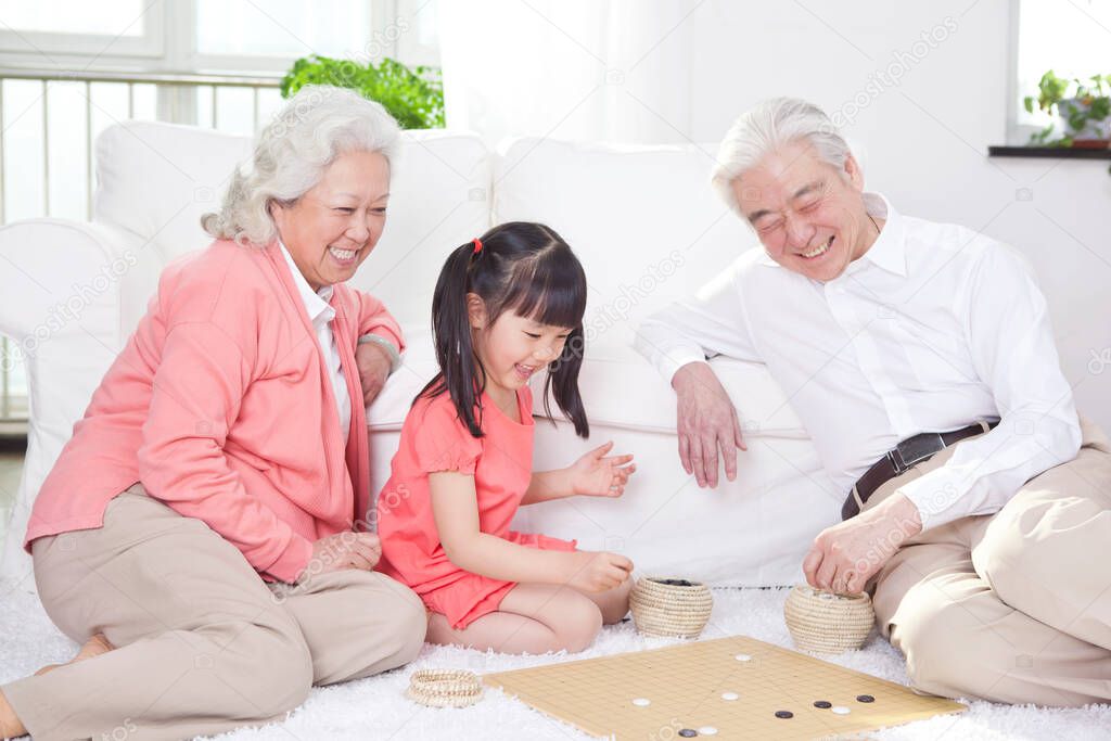 	Senior couple with granddaughter playing game of go	