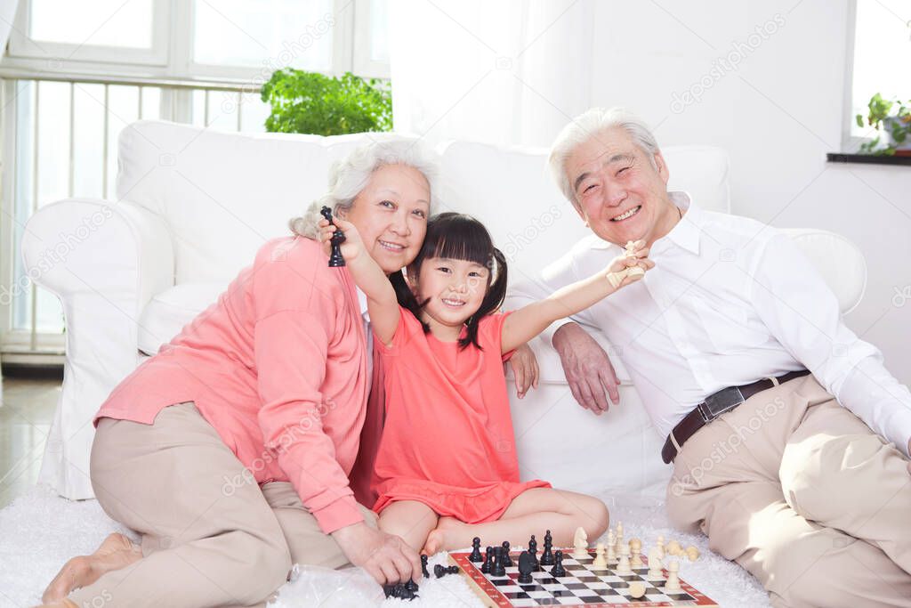 	Senior couple with granddaughter playing game of go	