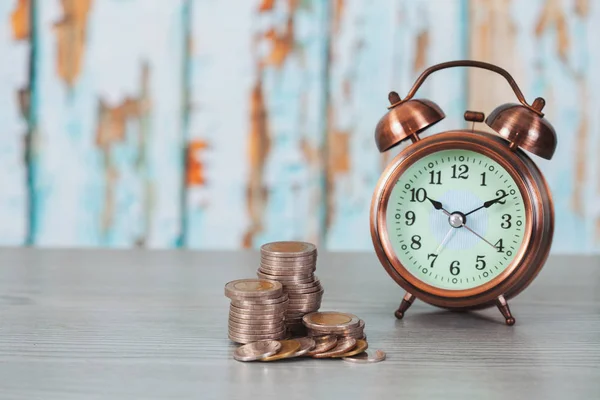 目覚まし時計 ビジネスファイナンス 将来のためのお金を節約 お金の概念と重なりコインのクローズ アップ — ストック写真