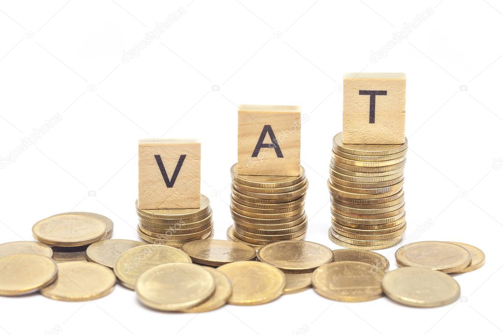 Word Vat Concept on wooden block over on stacked coins.