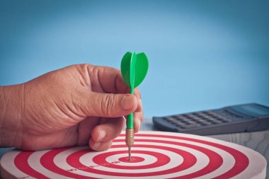 Dart arrow in hand on target dartboard ,Business success concept clipart