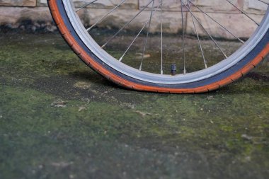 Eski bisiklet tekerleği düz lastik kirli yolda.