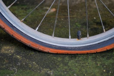 Eski bisiklet tekerleği düz lastik kirli yolda.