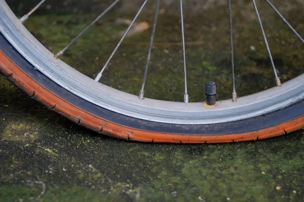 Eski bisiklet tekerleği düz lastik kirli yolda.
