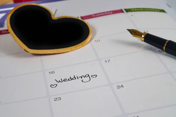 Reminder Wedding day in calendar planning with black heart sign and fountain pen