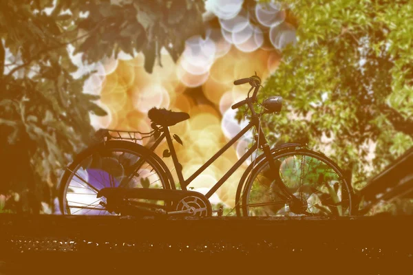 Silhueta bicicleta vintage com fundo de luz bokeh . — Fotografia de Stock