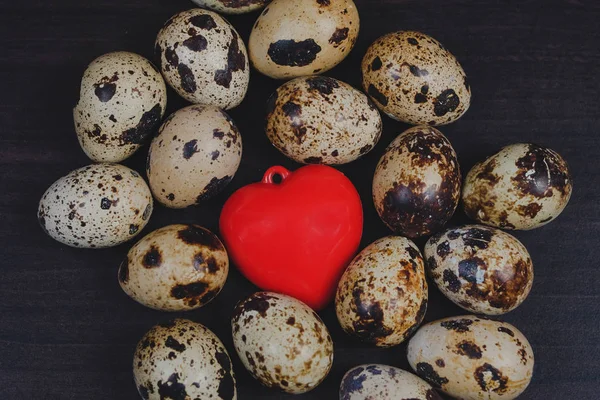 Fresh Quail eggs with red heart on background.Food and health co