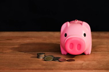 Natürmort kumbara ve sikke yığını masada.