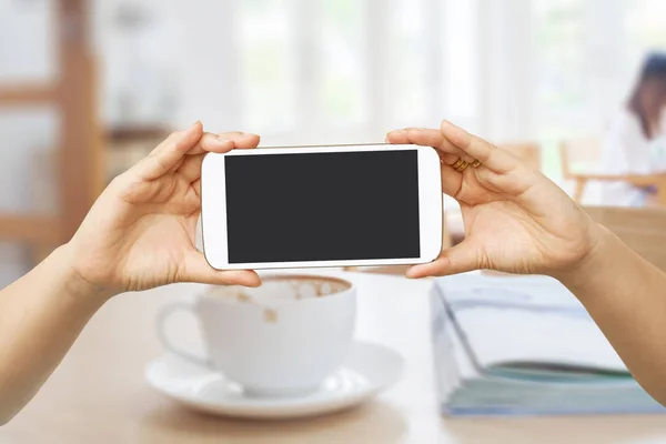 Hand Hold en touch screen mobiele telefoon, mobiel over wazig koffie — Stockfoto