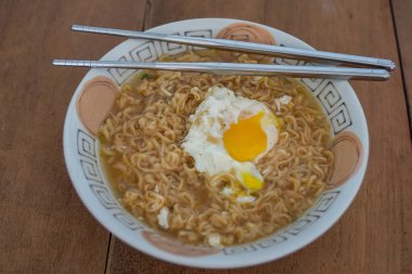 Ahşap arka plan üzerinde haşlanmış yumurta seti ile sıcak anlık erişte.