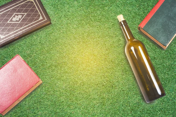 Text book and wine bottle on green grass . — Stock Photo, Image