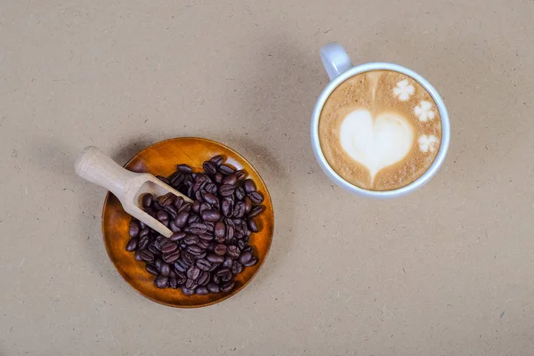 Heart sign on Late art coffee with fresh coffee bean on table.