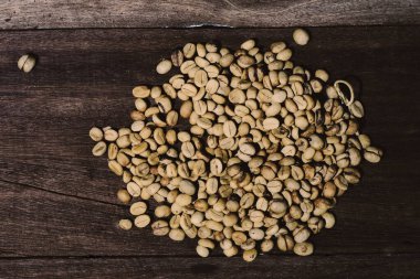 Ahşap masada organik çiğ kahve çekirdekleri.