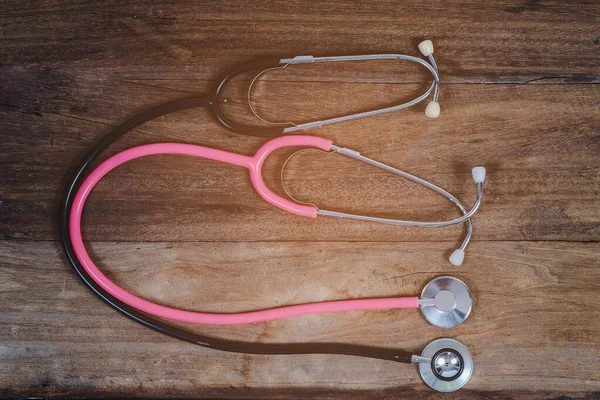 Pink and black Stethoscope on wood table. — Stock Photo, Image