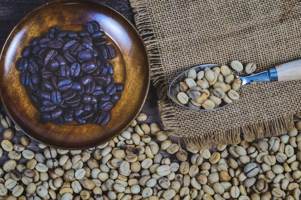 Organic Raw coffee beans with roaster coffee on wood dish.
