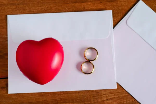 Bola sinal coração vermelho sobre invice carta com anel de casamento dourado — Fotografia de Stock
