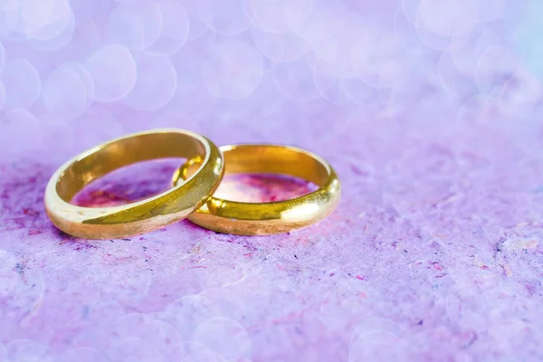 纸背上的双金色结婚戒指。婚礼概念. — 图库照片