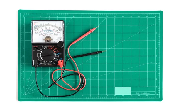 背景にVoltmeter作業ツールを使用した緑のグリッドカットマットまたはパッド — ストック写真