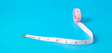 Renk arkaplanı üzerine bir mezura rulosu.