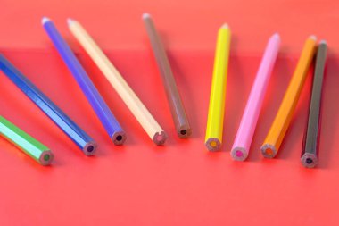 Kırmızı arkaplanda parlak renkli kalemler.