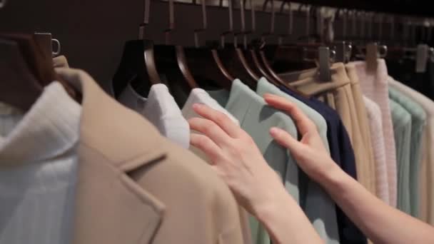 Eine Frau oder ein Mädchen wählt Kleidung im Geschäft, wir sehen nur ihre Hände — Stockvideo