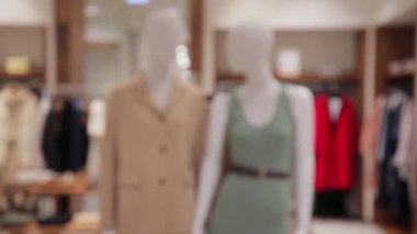 Beyaz mankenler, küçük bir mağazada yeni bir kadın giysisi koleksiyonu sergiliyor.