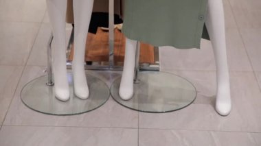 Beyaz mankenler, küçük bir mağazada yeni bir kadın giysisi koleksiyonu sergiliyor.