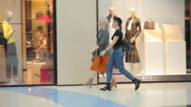 Geniş bir ticaret merkezi, farklı yaş ve cinsiyetlerden insanlar alışverişe gidiyor.