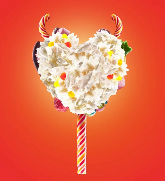 Devil heart Milk shake lolipop with sweets and whipped cream, front view. Sweet devil lolipop concept with whipped cream and devil horns, devil sweats. Front view of whipped cream of devils sweets