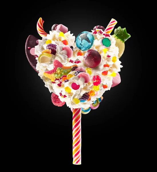 Sweet Lolipop v podobě srdce šlehačky s sladkosti, želé, pohled zepředu na srdce. Crazy freakshake potraviny trend. Čelní pohled šlehačkou srdce krém lízátko, plný berry a želé bonbóny, čokoláda — Stock fotografie