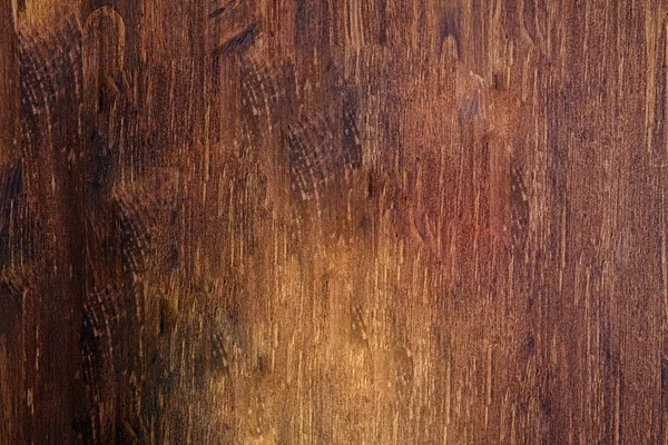深棕色木桌背景，下方有灯光。空质朴的老装饰木表面与严格的木制纹理 — 图库照片