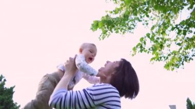 Genç mutlu anne doğada gülümseyen çocukla oynuyor. Anne kusar ve onu ağır çekimde yakalar.