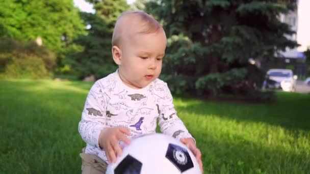 公園を歩いている彼の手にボールを持つ陽気な子供 スローモーション 彼の手の中に黒と白のサッカーボールを保持1歳の少年 公園で遊ぶ子供 — ストック動画