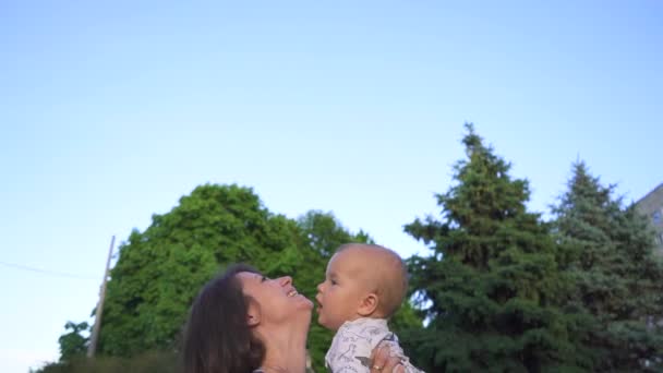 若い幸せな母は自然に笑顔の子供と遊ぶ 母親は赤ちゃんをスローアップし スローモーションで彼をキャッチ — ストック動画