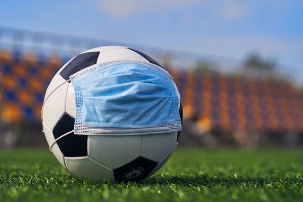  Siyah ve Beyaz Futbol Balosu Stadyumun Boş Koltukları 'nın Arkasında Tıbbi Maske Altında. Karantina zamanında futbol müsabakaları. COVID-19 Konsepti                