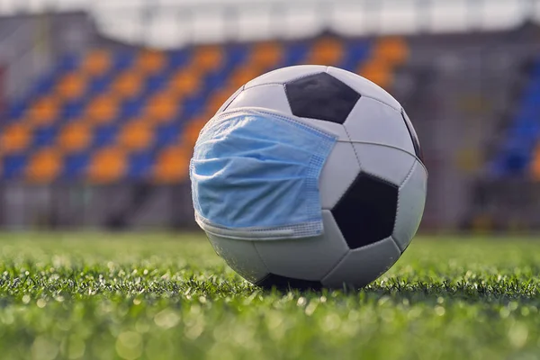  Siyah ve Beyaz Futbol Balosu Stadyumun Boş Koltukları 'nın Arkasında Tıbbi Maske Altında. Karantina zamanında futbol müsabakaları. COVID-19 Konsepti                