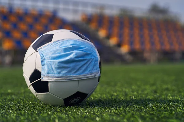  Siyah ve Beyaz Futbol Balosu Stadyumun Boş Koltukları 'nın Arkasında Tıbbi Maske Altında. Karantina zamanında futbol müsabakaları. COVID-19 Konsepti                