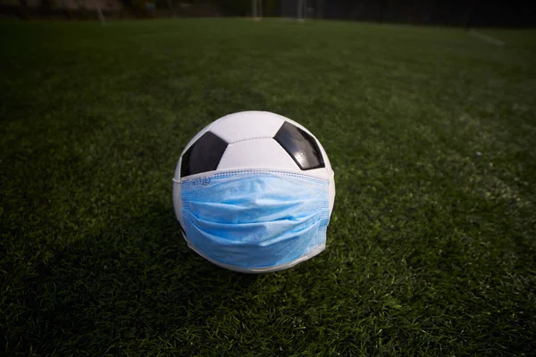 Medical Mask on Soccer Ball. Football Competition During  Coronavirus Pandemic
