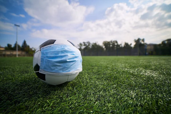 Futbol topunda tıbbi maske. Coronavirüs salgını sırasında futbol müsabakası              