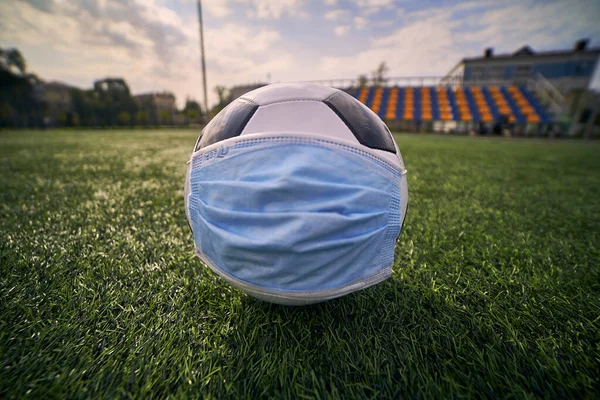  Siyah ve Beyaz Futbol Balosu Stadyumun Boş Koltukları 'nın Arkasında Tıbbi Maske Altında. Karantina zamanında futbol müsabakaları. COVID-19 Konsepti                