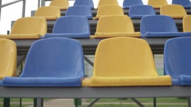 4K, Stadyumdaki Boş Plastik Koltuklar. Seyirci ve Hayranları Olmayan Futbol Stadyumu Tribününde Sarı ve Mavi Koltuklar