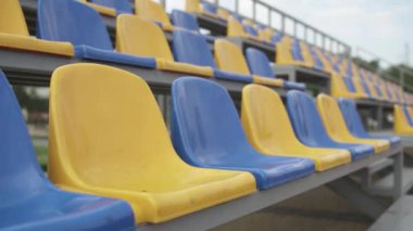 4K, Stadyumdaki Boş Plastik Koltuklar. Seyirci ve Hayranları Olmayan Futbol Stadyumu Tribününde Sarı ve Mavi Koltuklar