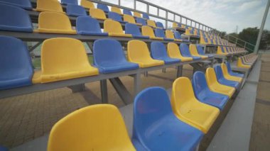 4K, Stadyumdaki Boş Plastik Koltuklar. Seyirci ve Hayranları Olmayan Futbol Stadyumu Tribününde Sarı ve Mavi Koltuklar